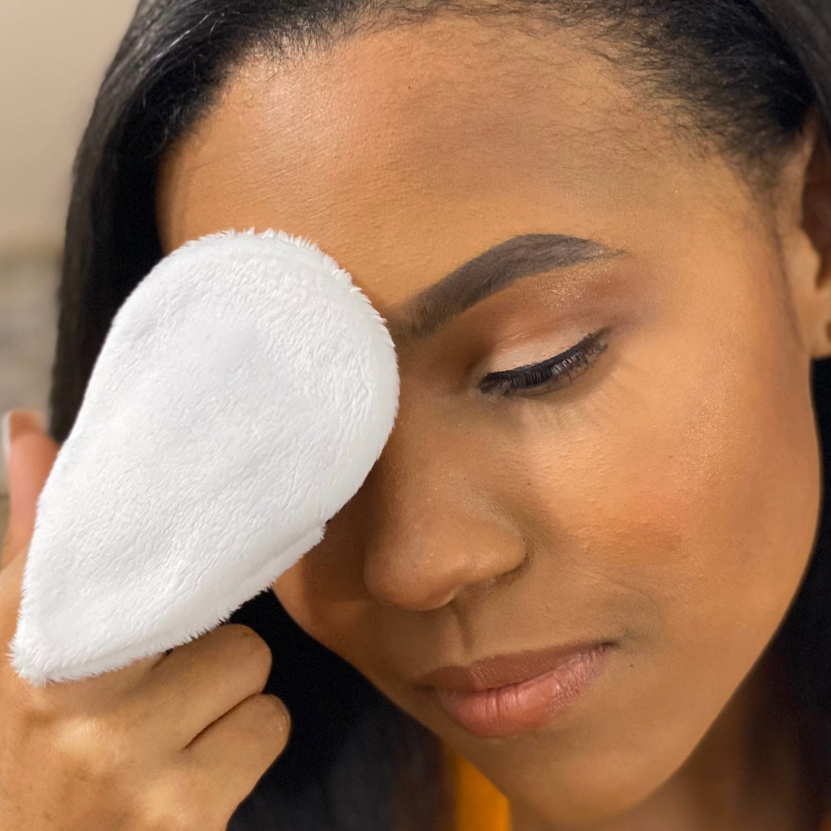 Young woman using white Mitty to cleanse skin
